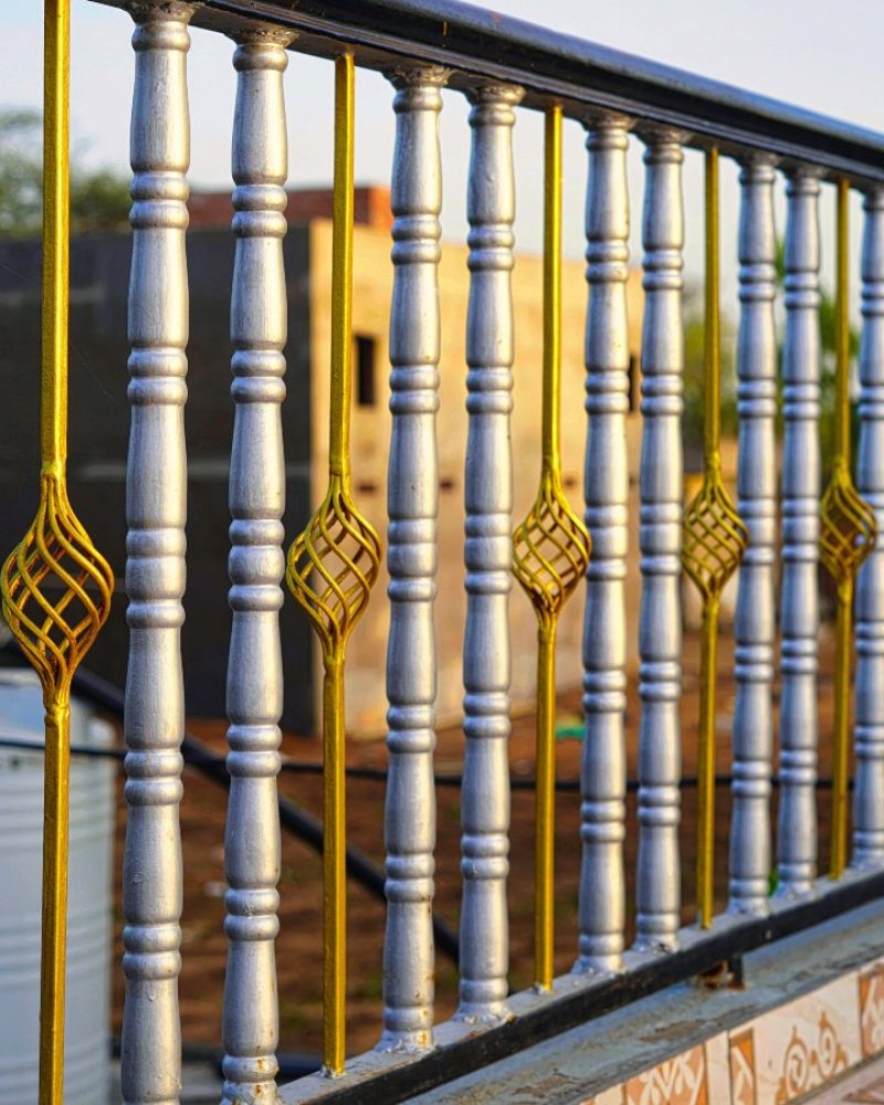 Beautiful decorative cast metal wrought fence with artistic forging. Iron guardrail close up. Golden chromium silver fence closeup.